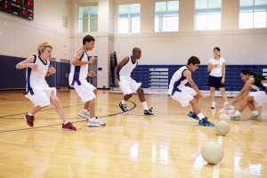 Students run on a basketball court in PE class